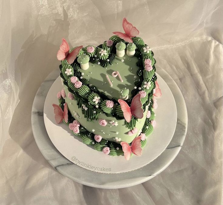 a heart shaped cake on a plate with pink and green flowers in the shape of a clock