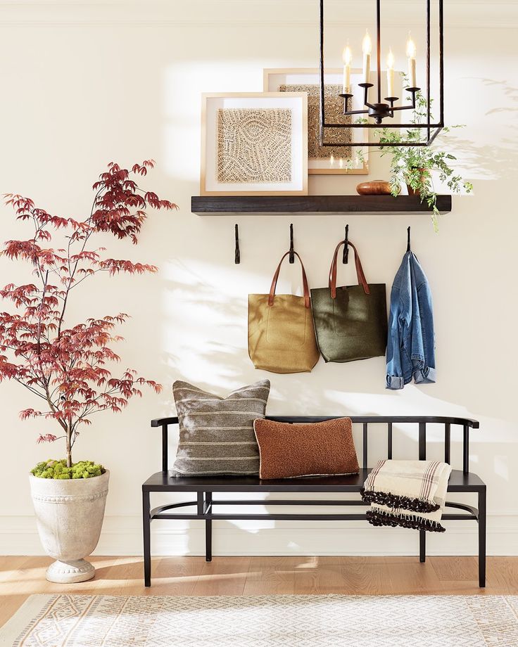 a bench with two purses on it next to a potted plant and candles