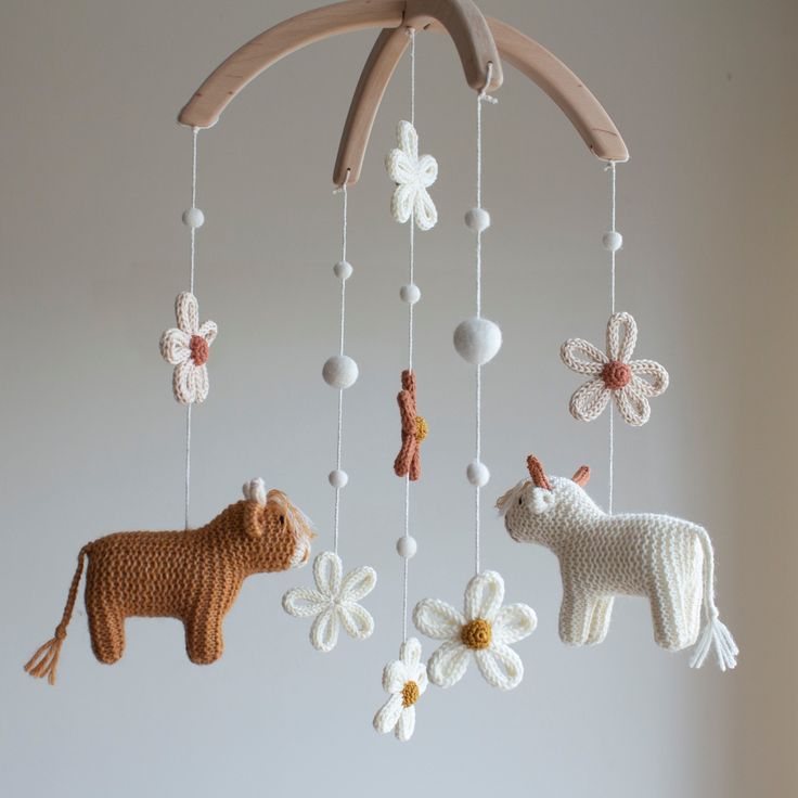 crocheted animals and flowers hanging from a wooden mobile in the shape of an animal