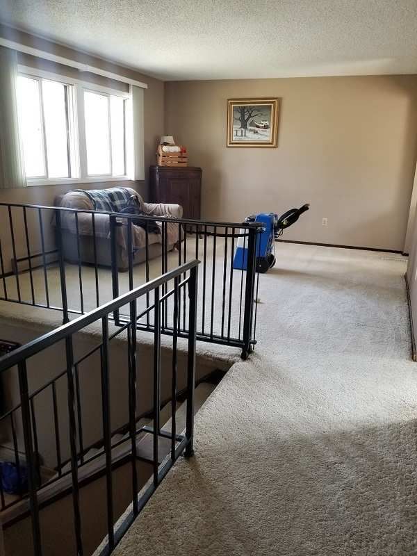 a living room filled with furniture next to a stair case in front of a window