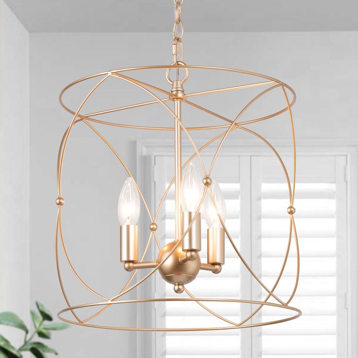 a gold chandelier with three lights hanging from it's center and two candles in the middle