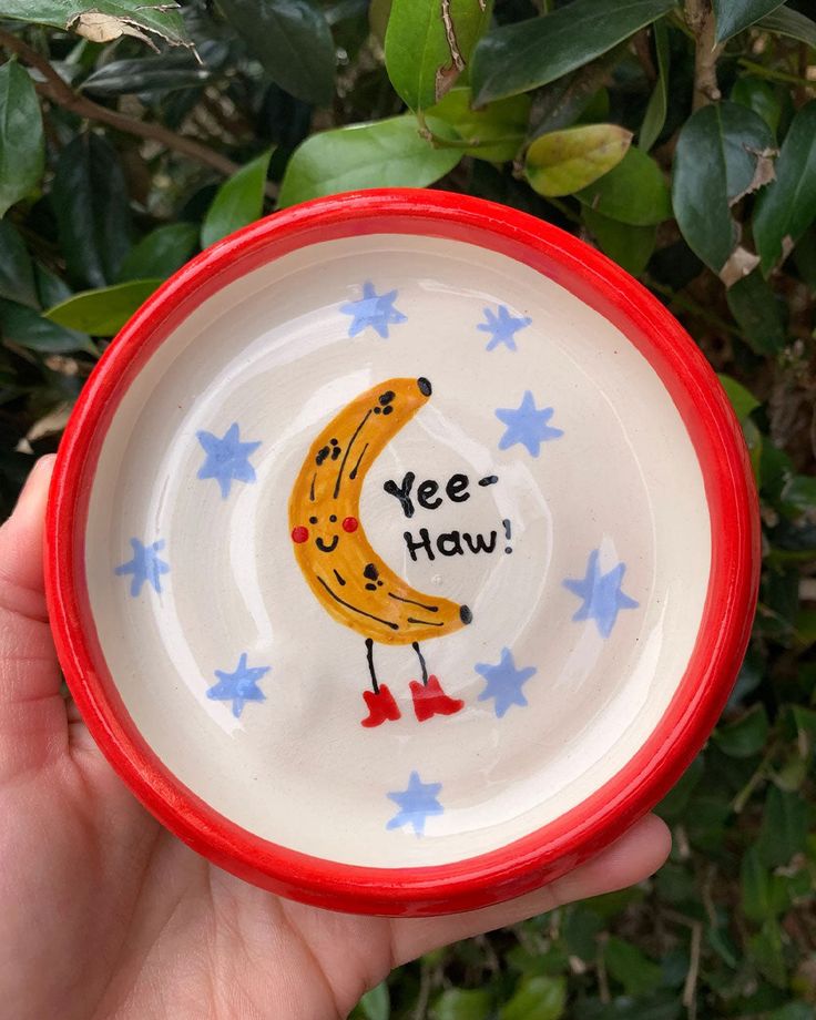 handmade trinket tray with red trim and yee-haw banana in the center Pottery Idea Painting, Trinket Tray Painting Ideas, Cute Painted Pottery, Hand Painted Bowl, Silly Ceramics, Clay Bowl Painting Ideas, Trinket Dish Painting Ideas, Diy Pottery Painting Ideas, Painting Dishes