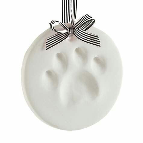 a white ceramic ornament with a bow on it's end and paw prints