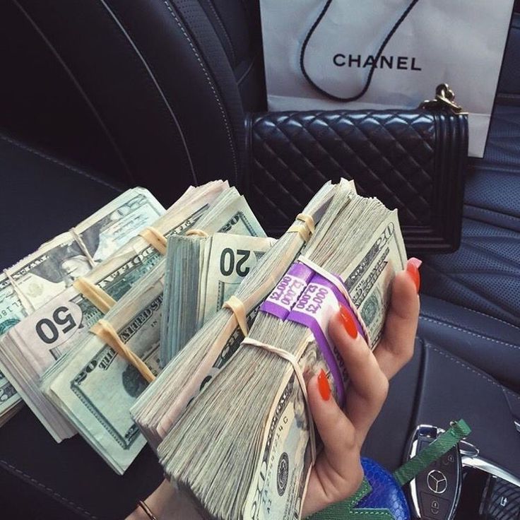 a woman holding cash in her hand while sitting in the back seat of a car