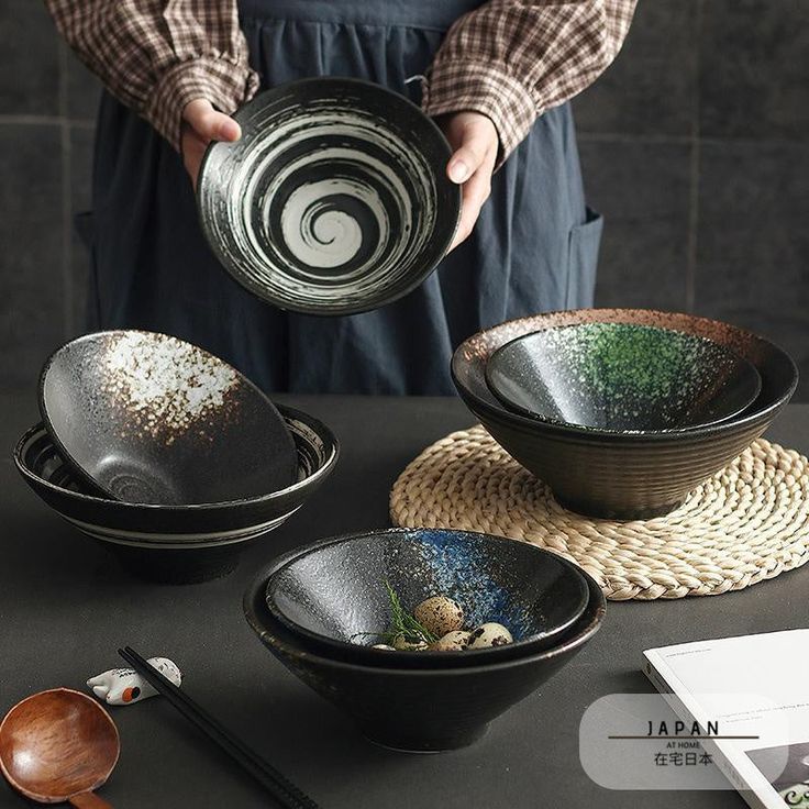 a person holding a bowl over some bowls on a table