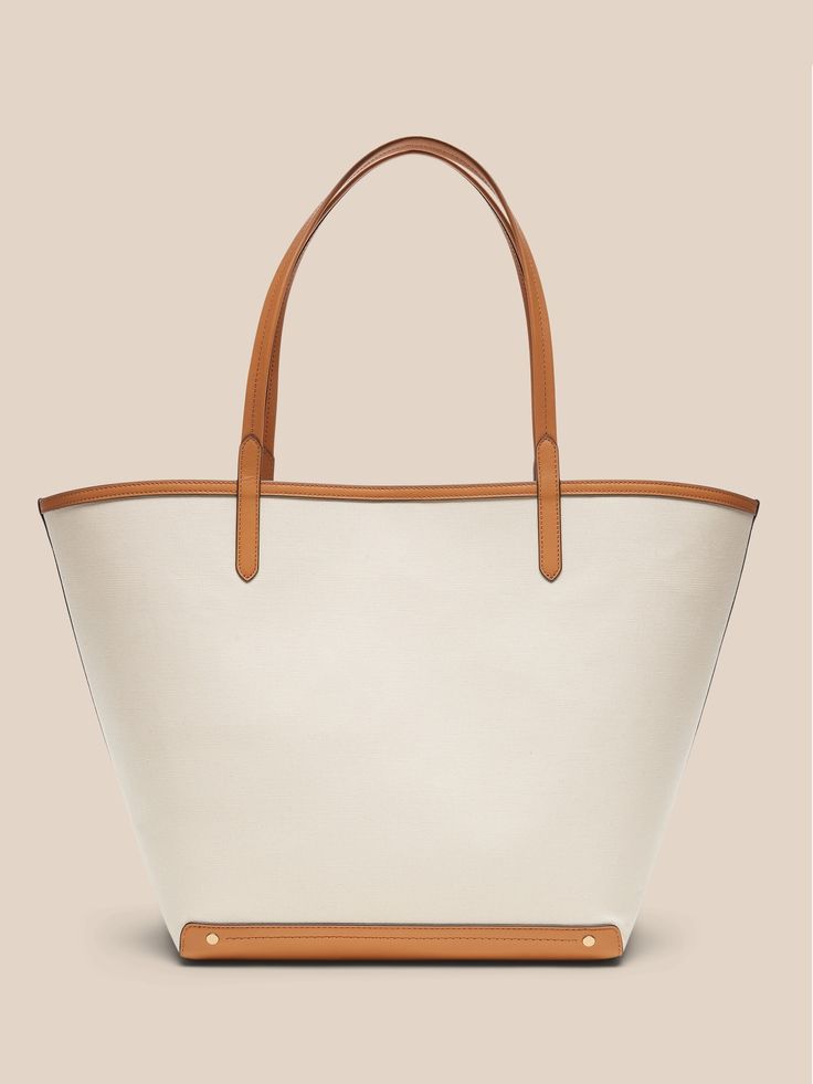 An elegant companion to everyday style, this classic tote goes anywhere with ease with spacious storage, sturdy leather trim, and a snap closure.  Sturdy leather handles.  Open top with snap closure.  Height: 16" (41cm) Width: 25" (63cm) Depth: 8" (2 Elegant Coated Canvas Bucket Bag For Errands, Shopping Bucket Bag With Leather Trim, Coated Canvas Tote Bucket Bag, Canvas Bucket Bag With Leather Trim For Shopping, Coated Canvas Bucket Bag Tote For Errands, Chic Leather Bucket Bag With Canvas Lining, Rectangular Coated Canvas Bucket Bag With Leather Trim, Canvas Bucket Bag With Leather Trim Tote, Classic Bucket Bag With Handles For Travel