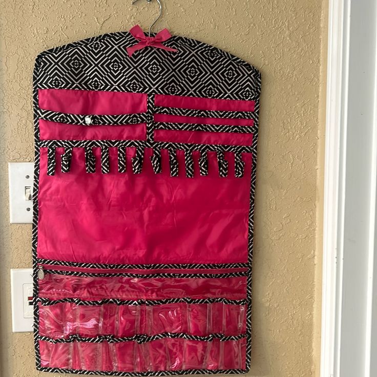 a pink and black purse hanging on the wall