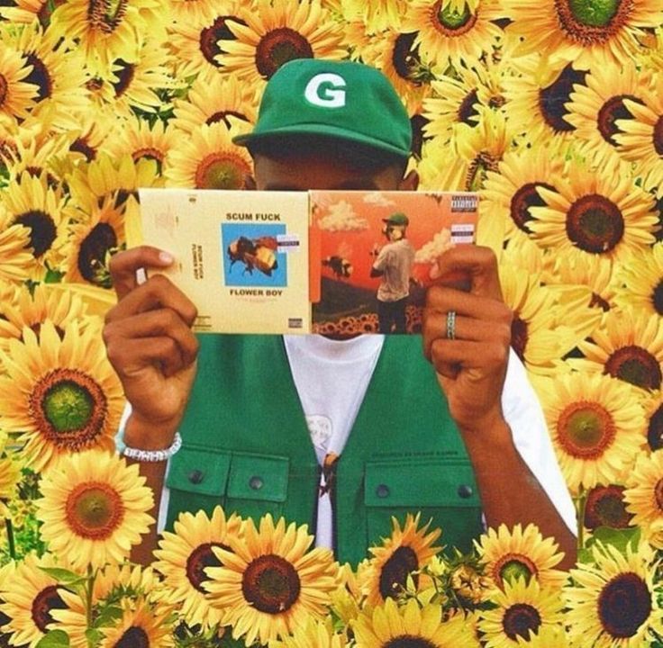 a man reading a book in front of sunflowers with the letter g on it