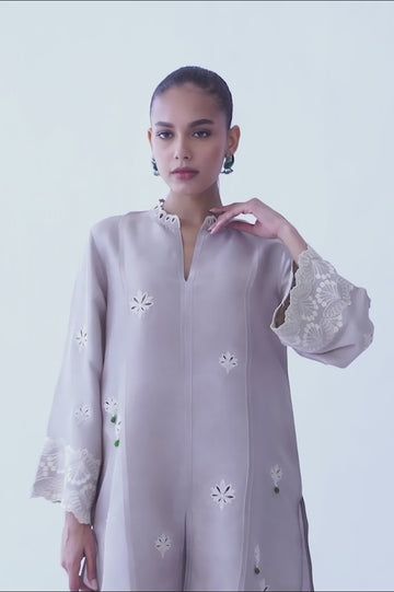 A beautifully crafted silver rawsilk fabric with floral eyelet detailing and embroidered sleeves. The look is completed with matching co-ord izaar with embroidered hem. Silk Sets With Chikankari Embroidery, Designer Wear Spring Kurta With Set-in Sleeves, Designer Spring Kurta With Set-in Sleeves, Spring Festive Kurta With Set-in Sleeves, Silk Tunic Sets For Wedding, Festive Embroidered Top For Eid, Spring Sets With Resham Embroidery Tunic, Spring Tunic Sets With Resham Embroidery, Traditional Spring Kurta With Set-in Sleeves