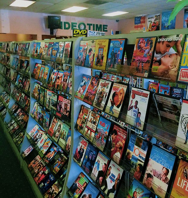 there are many movies on the shelves in this store that is filled with magazines and dvds