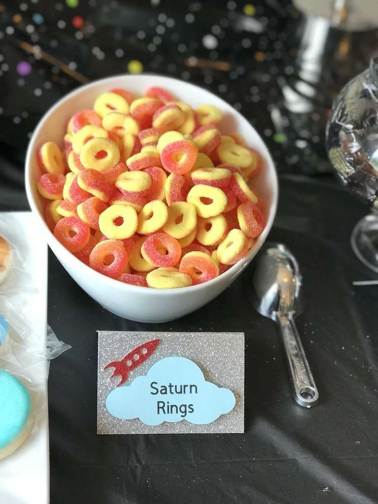 a bowl of cereal sitting on top of a table next to cookies and other items