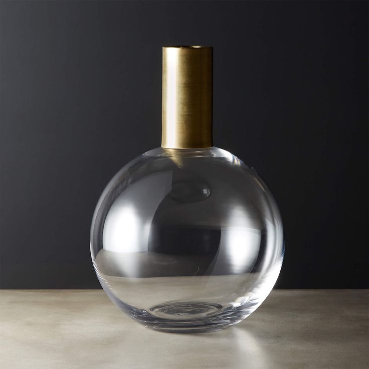 a clear glass bottle sitting on top of a table next to a brown object with a gold cap