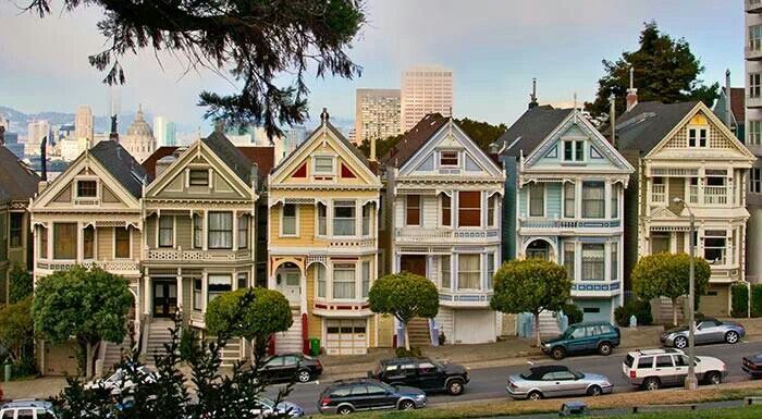 the houses are painted in different colors and sizes, along with cars parked on the street