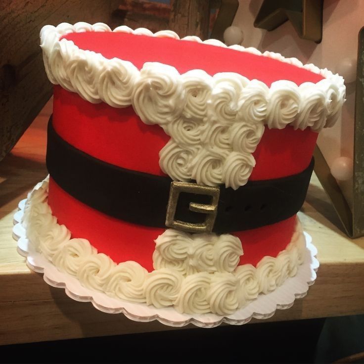 a red and white cake with a santa claus hat on it's top, sitting on a table