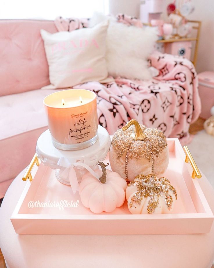 a tray with candles, pumpkins and other decorations on it in a pink living room