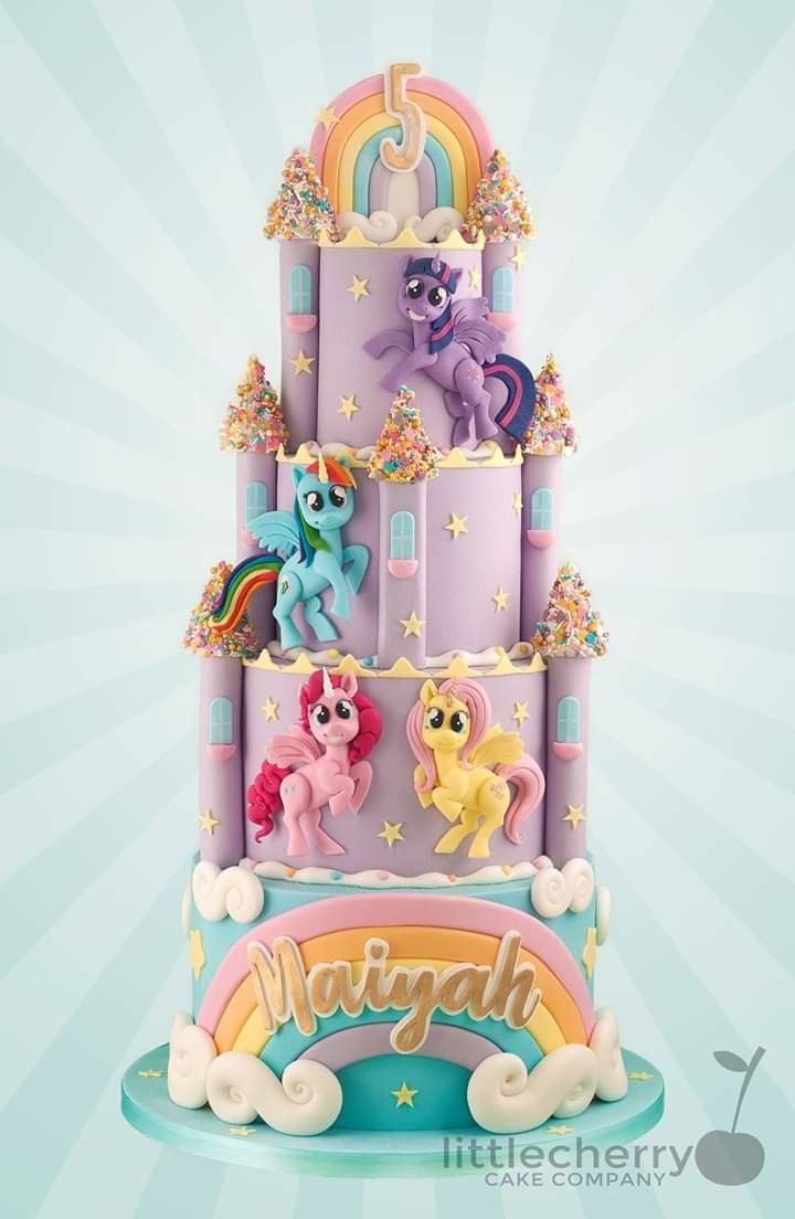 a three tiered cake decorated with rainbows and ponies on top of it