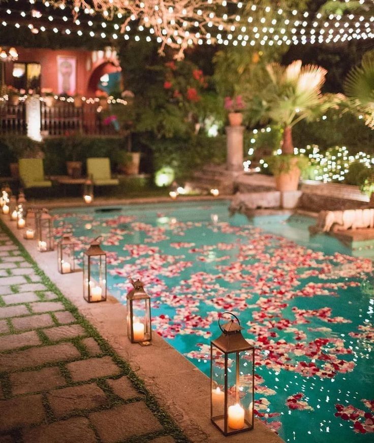 an outdoor pool with candles and flowers on it