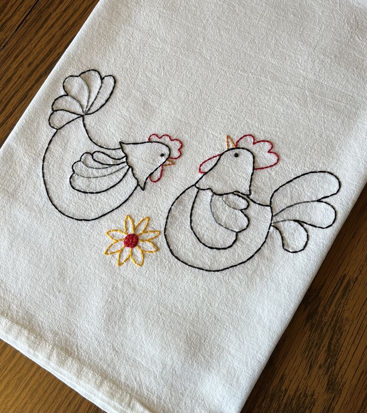 a white towel with two embroidered chickens on it