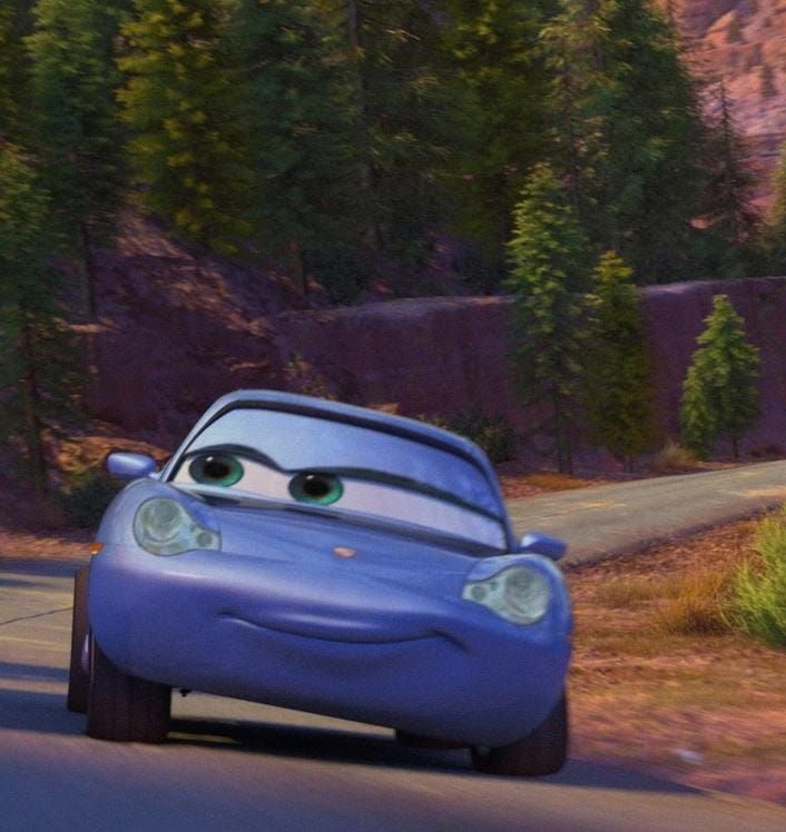 a blue car driving down a road next to trees