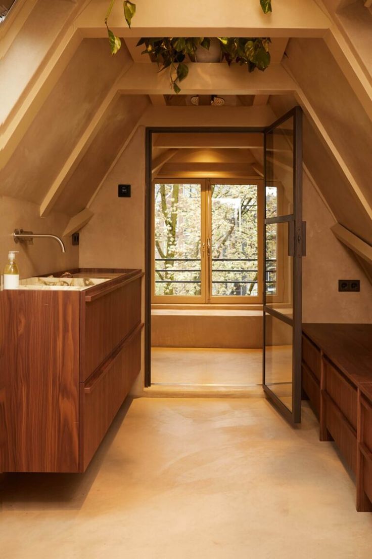 an attic bathroom with wooden cabinets and windows