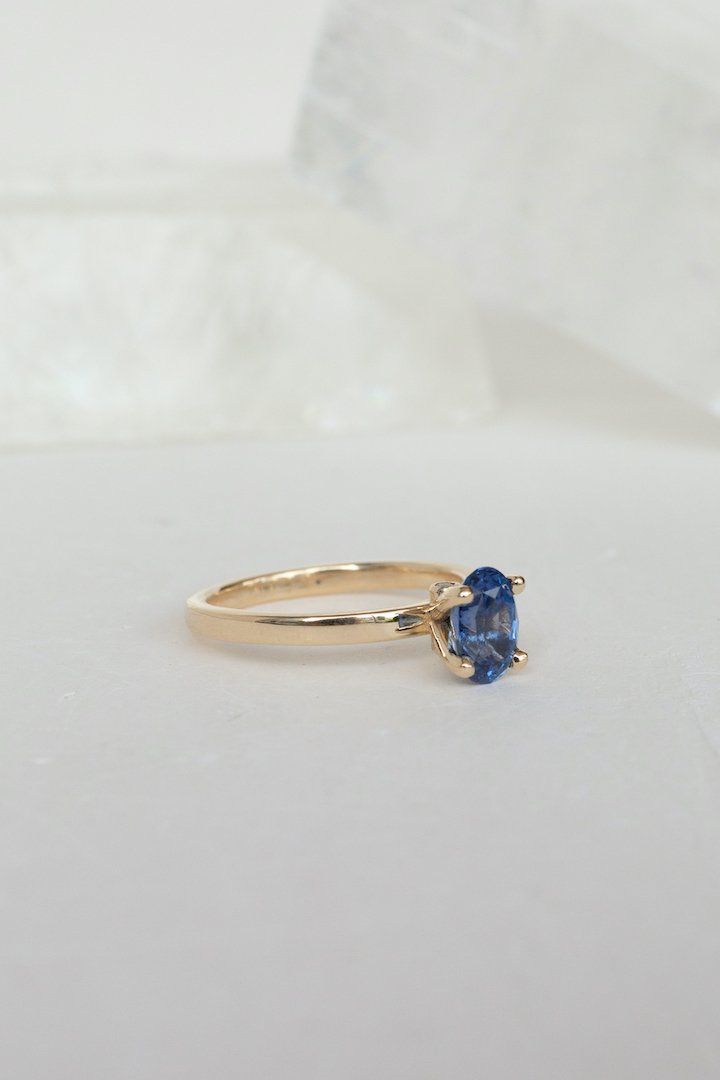 Blue sapphires come in all shades and clarity - this oval-shaped gem is wonderfully clear and sparking, with a rich, deep shade of blue that can change to more purple in different lighting. We've set this sapphire in a simple, airy prong with two tiny white diamonds under it. The overall effect is one of whimsy and delicacy, but this ring will be an heirloom for generations. - 1.45ct sapphire﻿- 0.03ctw diamonds﻿- 14k recycled yellow gold﻿- 2mm band﻿- High polish finish ﻿This ring ships immediate Classic Blue Sapphire Gemstone Ring, Classic Blue Sapphire Birthstone Ring, Timeless Blue Sapphire Ring, Timeless Blue Oval Sapphire Ring, Classic Blue Sapphire Ring With Prong Setting, Timeless Oval Sapphire Ring With Prong Setting, Blue Sapphire Ring With Marquise Cut Center Stone, Oval Blue Birthstone Ring, Oval Sapphire Birthstone Ring With Center Stone