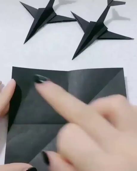 someone is making origami birds out of black paper and glues them together