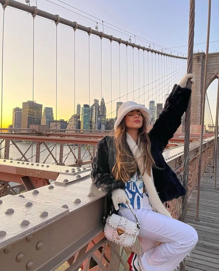 a woman is posing on the side of a bridge with her arms in the air