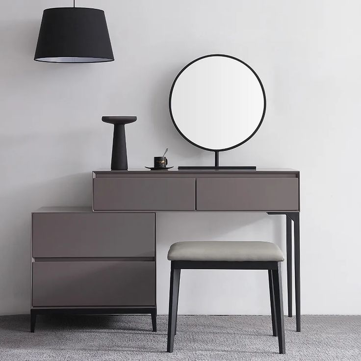 a vanity with a mirror, stool and lamp in a white walled room next to a gray wall