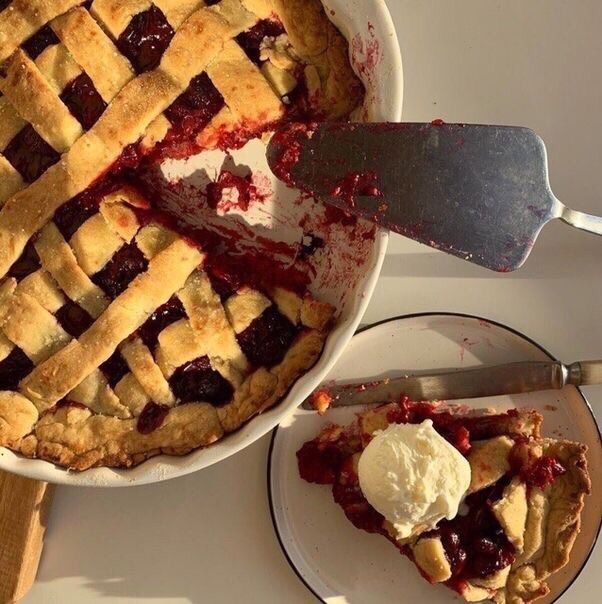 a pie is sitting on a plate with a knife next to it and another pie in the background