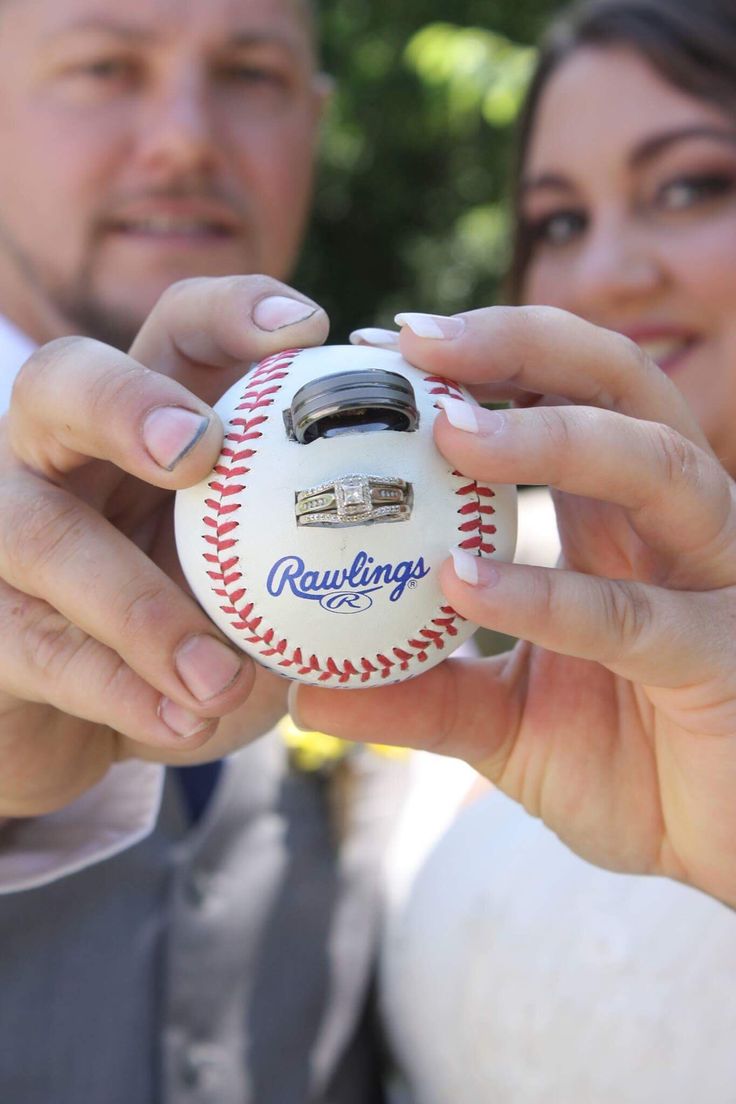 a man and woman holding up a baseball