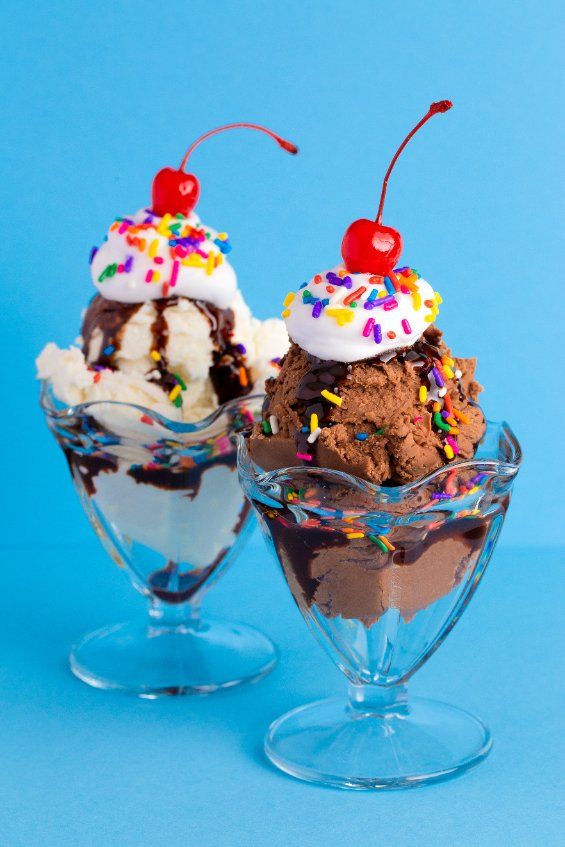 two ice cream sundaes with sprinkles and cherries on top