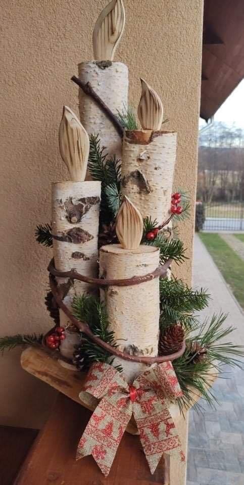 a christmas tree made out of birch logs with pine cones and bows on the top