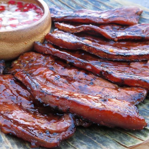 there is a bowl of sauce next to some ribs