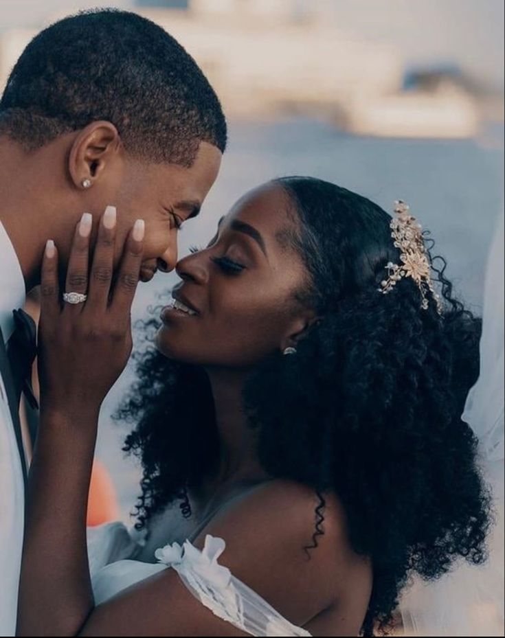 a bride and groom kissing each other on their wedding day in front of the ocean