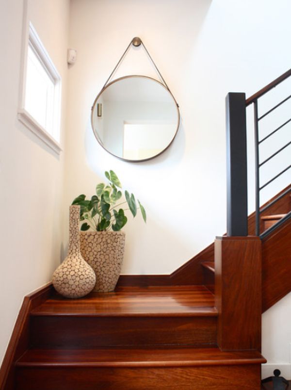 there is a potted plant sitting on the stair case next to the mirror and window