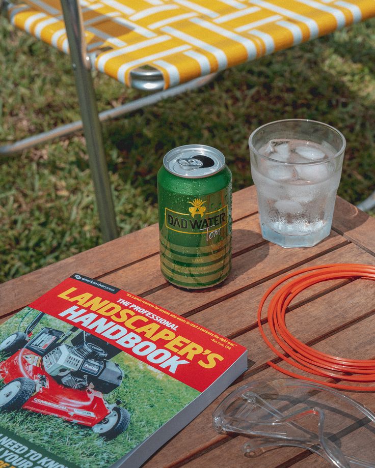 a lawn mower sitting on top of a wooden table next to a can of beer