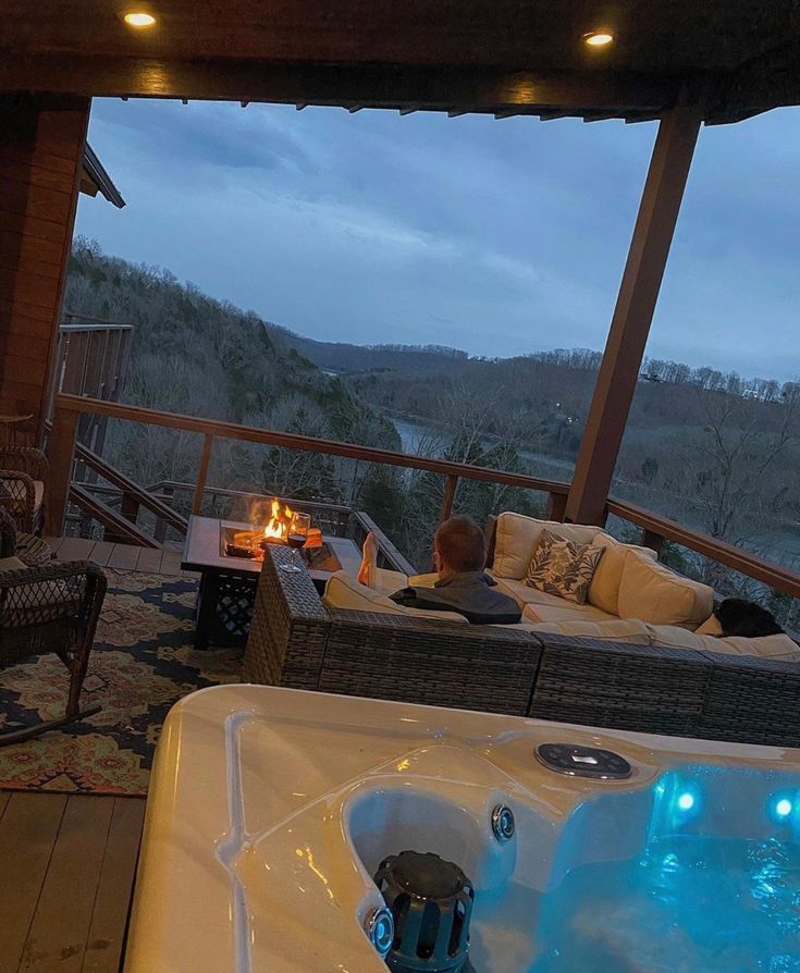 a hot tub sitting on top of a wooden deck next to a fire pit in the middle of a living room