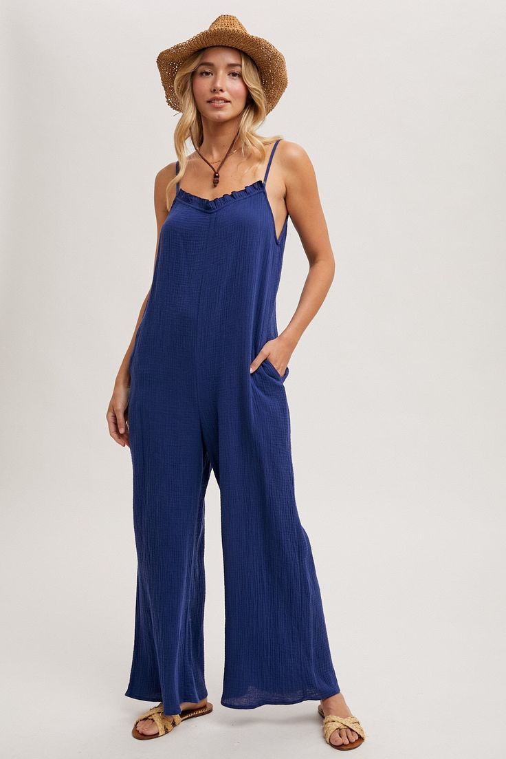 A cotton material jumpsuit with adjustable spaghetti straps. This jumpsuit has a ruffled neckline, wide legs, and side pockets. Style with wedges and a cute brim hat for lunch with your gal pals. Model is 5'10" and wearing her true size Small. Small: Bust 17", Length 57.5" 100% Cotton Solid Cotton Jumpsuits And Rompers With Spaghetti Straps, Adjustable Straps Jumpsuits And Rompers For Day Out, Trendy Cotton Jumpsuits And Rompers With Adjustable Straps, Cotton Jumpsuits And Rompers With Spaghetti Straps And Pockets, Trendy Cotton Beach Overalls, Casual Ruffled Overalls For Spring, Summer Overalls With Adjustable Straps, Trendy Cotton Overalls For The Beach, Chic Cotton Jumpsuit With Ruffles