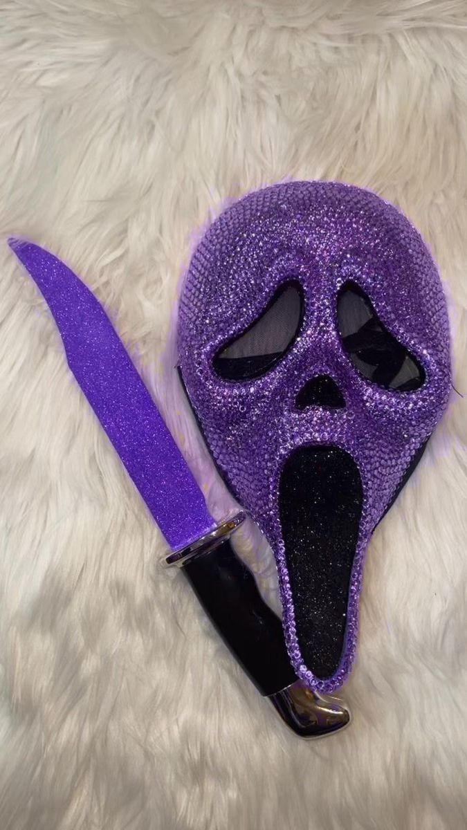 a purple mask with a knife sticking out of it's mouth on a white fur surface