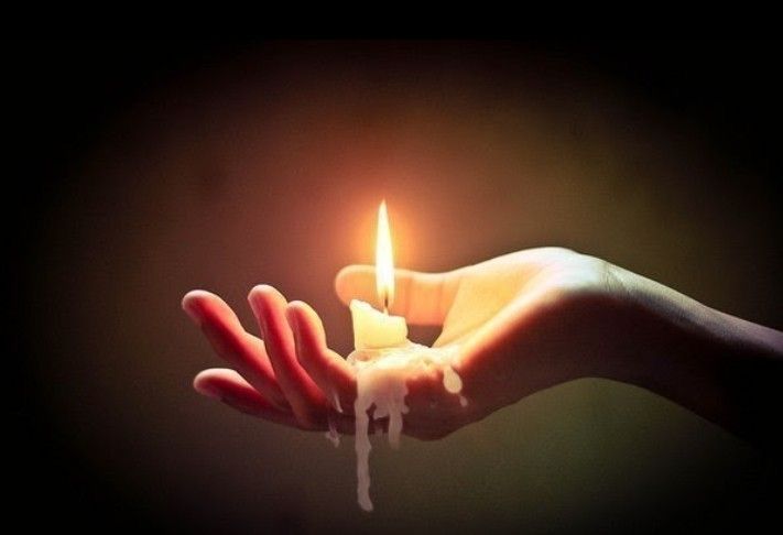 a person holding a candle in their hand with the light on it's end