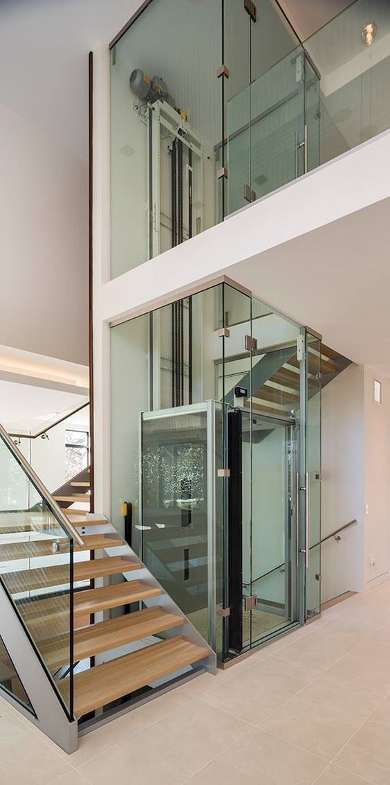 an open staircase with glass railing and wooden handrails in a modern home setting