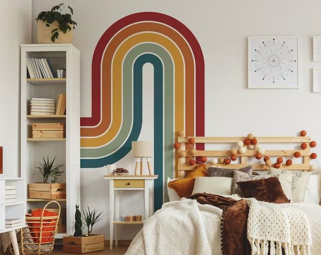 a bed room with a neatly made bed and a rainbow wall mural