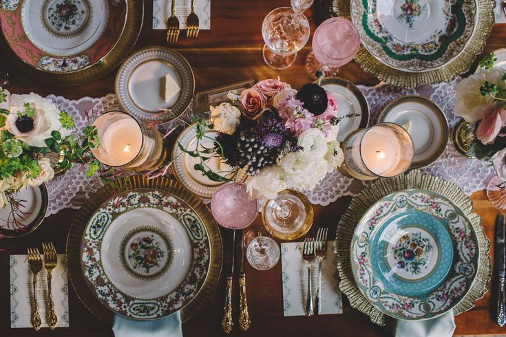 the table is set with plates, silverware and flowers