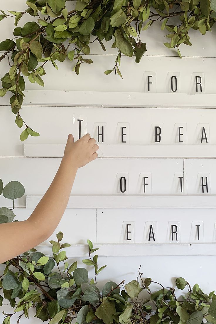 a person writing the word for the bead of the earth on a white board surrounded by greenery