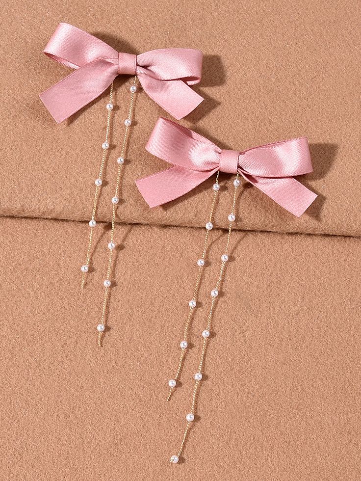 two pink bows and pearls hang from the side of a coat rack on a wall