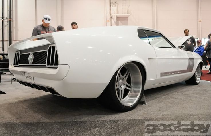 a white car is on display in a showroom with people looking at the cars