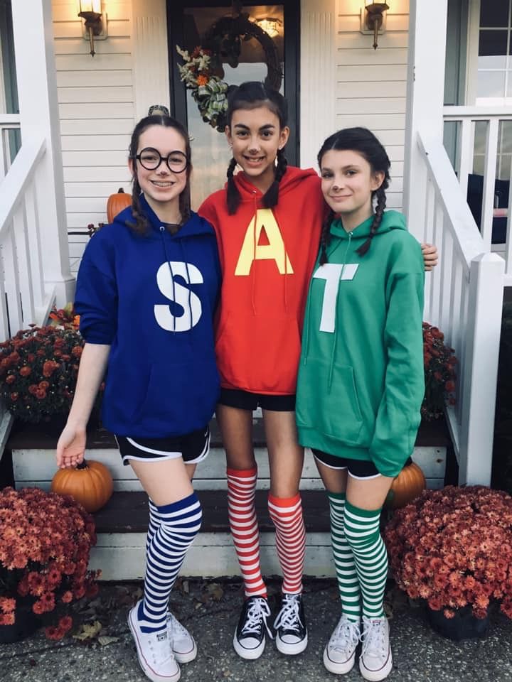 three girls in halloween costumes standing on the front steps of a house with their arms around each other