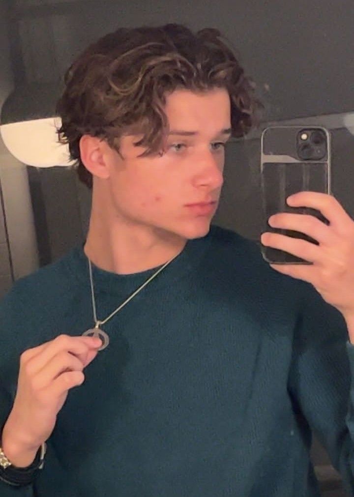 a young man taking a selfie in front of a mirror with his cell phone