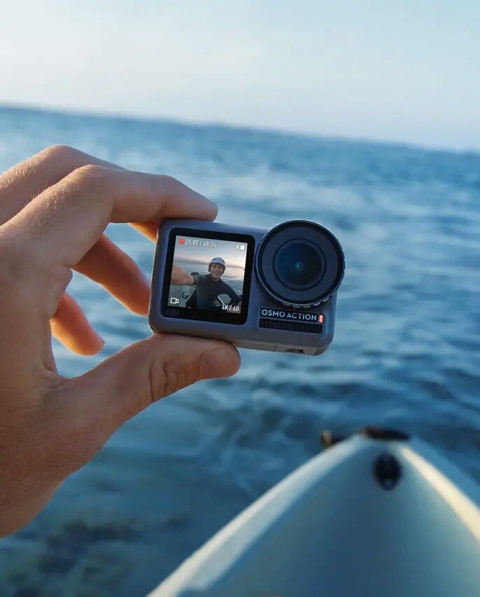 a person holding up a camera to take a photo on a boat in the water