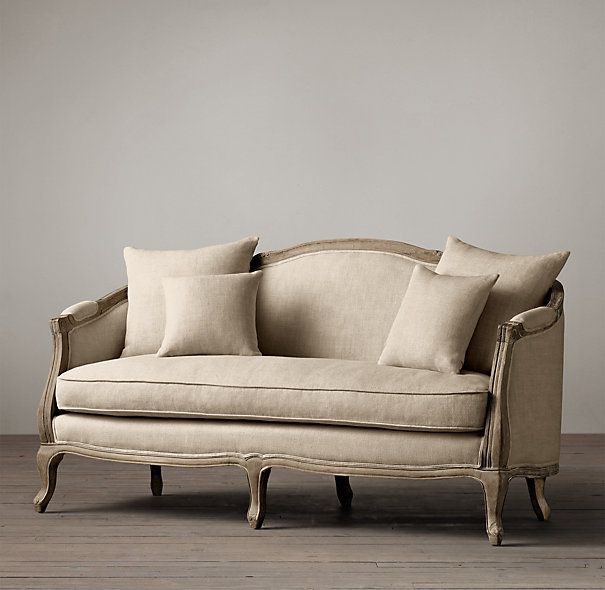 a couch with pillows on top of it in front of a gray wall and wooden floor